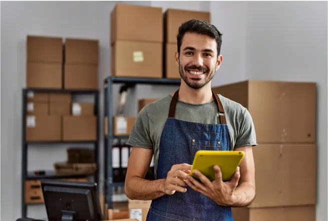 Smiling man wearing an apron holding a tablet