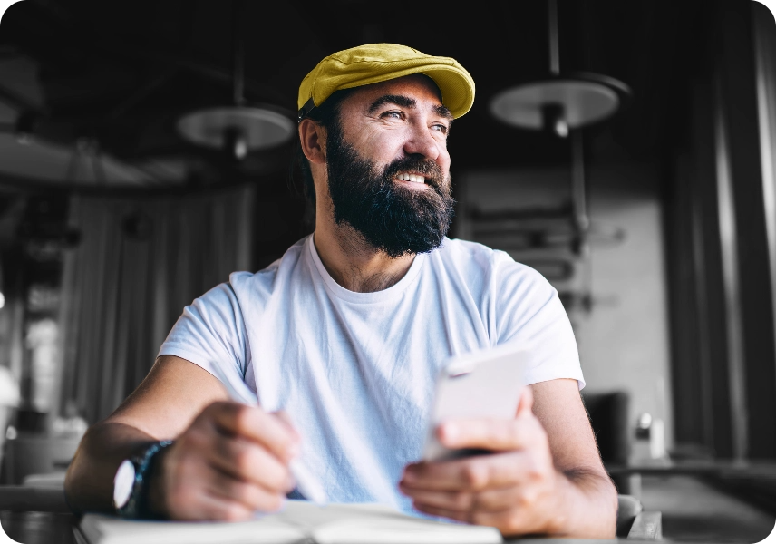 A man working holding his phone in a yellow hat