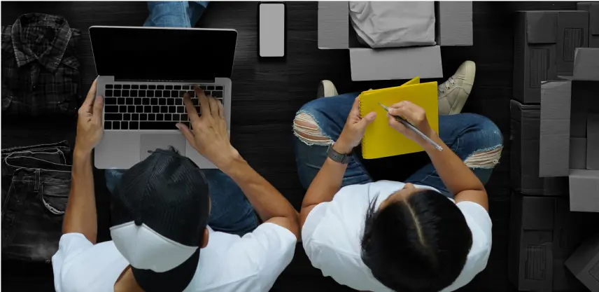 Two people working with a computer and a notepad fulfilling an order