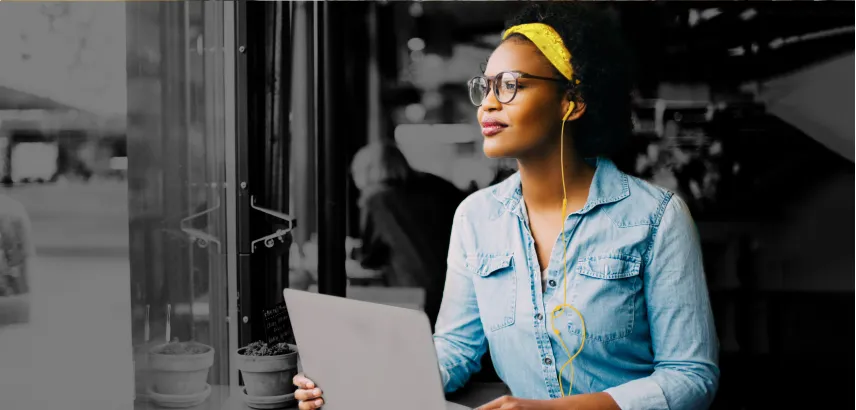 Woman wearing a yellow headband, glasses, with earbuds working